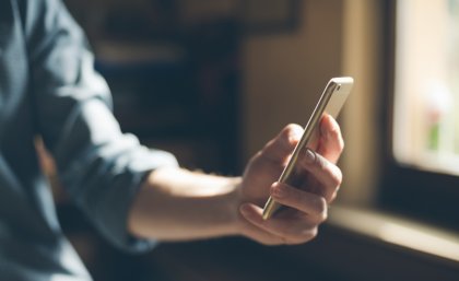 A hand holding a phone, texting.